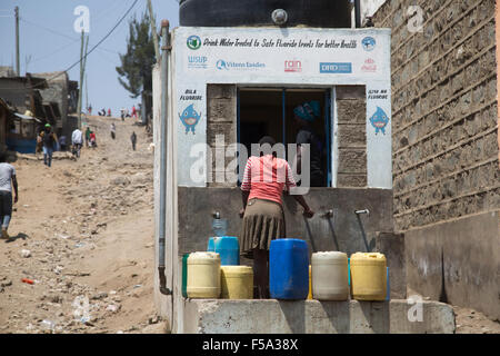 Frau mit Wasserbehältern sammeln erschwinglichen behandelt Trinkwasser Bohrloch Kamere Naivasha, Kenia Stockfoto