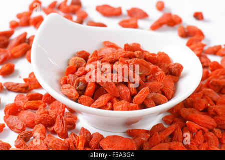 Getrocknete Goji Beeren in und neben kleinen Schüssel Stockfoto