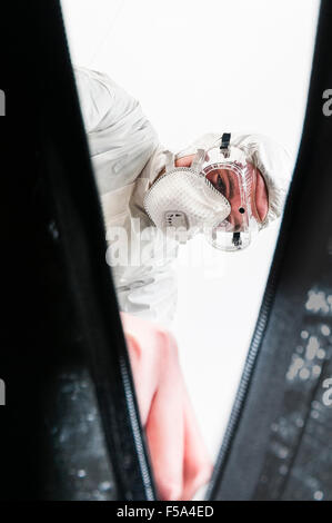 Eine Szene des Verbrechens Officer (SOCO) Schutzmaske und Schutzbrille tragen, einen Leichensack Reißverschlüsse (Sicht von innen Tasche) Stockfoto