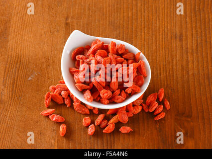 Getrocknete Goji Beeren in und neben kleinen Schüssel Stockfoto