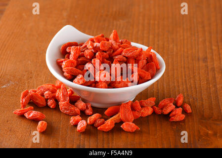 Getrocknete Goji Beeren in und neben kleinen Schüssel Stockfoto