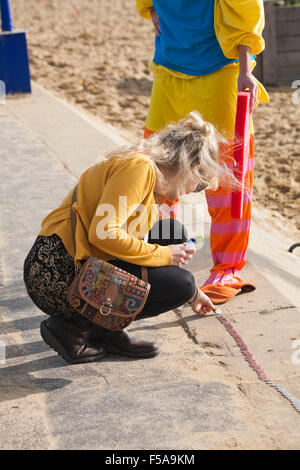 Bournemouth, Dorset, UK. 31. Oktober 2015. Ein Versuch ist im Gange, eine Meile von 10-Cent-Stück zwischen Bournemouth and Boscombe Piers zu bauen. Die Veranstaltung mit dem Titel Halloween Silber Meile, ist zugunsten der AOK Rucksack Reiz, bietet Notfall Rucksäcke von Hilfsgütern für neue Obdachlose Menschen, die von professionellen Agenturen identifiziert. Jemand berechnet, dass eine Meile ist offenbar 1609344 Millimeter, ein zehn-Cent-Stück ist 24 Millimeter Durchmesser, also vorausgesetzt, eine genaue schnurgeraden Meile und lückenlos 67056 Münzen Wert £6705,60 benötigt werden Stockfoto