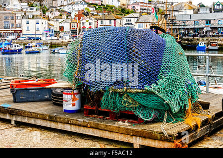 Fanggeräte, bedeckt mit grünen Fischernetze steht auf Holzpaletten gegenüber der Stadt im malerischen Hafen von Brixham Stockfoto