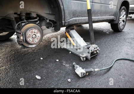 Räder auf ein Auto ersetzen, hält Jack den Körper in angehobener Stellung Stockfoto