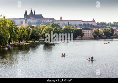 Menschen in Paddelboote in Moldau, Pragerburg und Strelecky Insel im Hintergrund, Prag, Tschechische Republik Stockfoto