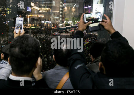 Menschen fotografieren durch ein Fenster um die kostümierten Partygänger auf Tokios Shibuya berühmten Gerangel Kreuzung während der Halloween-Feier am 31. Oktober 2015, Tokio, Japan. Versammeln Sie jedes Jahr Tausende von jungen japanischen sich in Shibuya und Roppongi für Halloween. In diesem Jahr das Tokyo Metropolitan Government fordert die Partygänger, die Straßen sauber mit dem Slogan "Saubersten Halloween in der Welt" zu halten und durch die Verteilung von 300.000 spezielle Müll Taschen kostenlos als Teil der Halloween & Tokio-Aktion. © Rodrigo Reyes Marin/AFLO/Alamy Live-Nachrichten Stockfoto