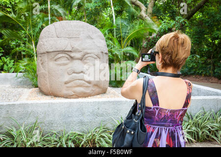 Weibliche Touristen fotografiert die Olmeken Steinbildhauen kolossale Kopf in La Venta Park, Villahermosa, Tabasco, Mexiko. Stockfoto