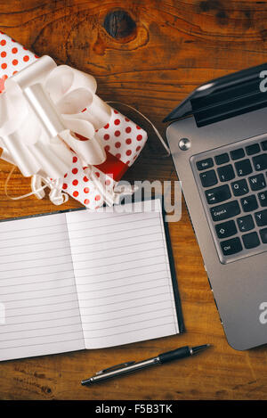 Büro-Geburtstags-Überraschung eingewickelt vorhanden Holz Schreibtisch mit Laptop-Computer und Notebook, Ansicht von oben zu öffnen. Stockfoto