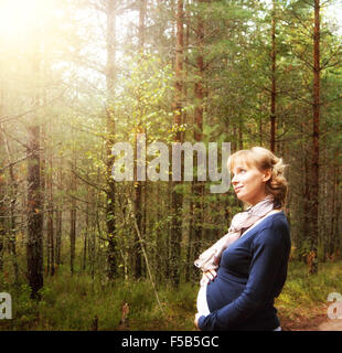 Schwangere Frau im Wald im Morgenlicht Stockfoto