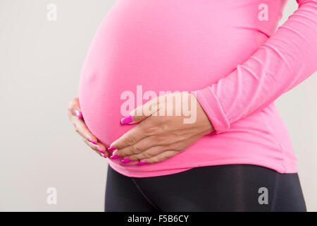 Schwangere Frau hält auf ihren geschwollenen Bauch Stockfoto