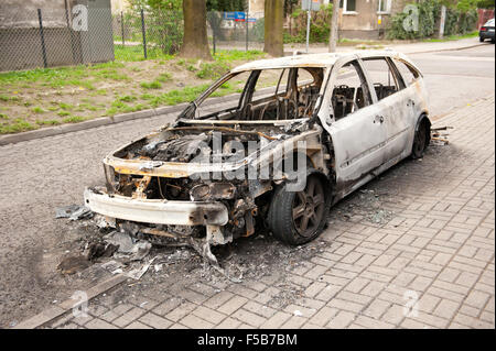 Verbrannte weißes Autowrack auf dem Bürgersteig in Polen, verwöhnte Auto in Feuerunfall, verkohlte Asche Brandstiftung Vorfälle und Junk-e-Fahrzeug... Stockfoto