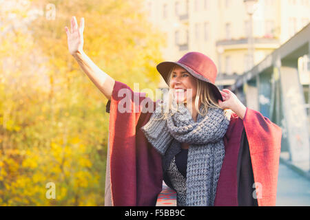 Frau im Herbst auf der Brücke stehen und winken mit jemandem Stockfoto