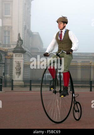 Ein Mann, in historischen Kostümen Zyklen vorbei an Buckingham Ort, auf einem alten Hochrad, während die von London nach Brighton Veteran Car Run. Stockfoto