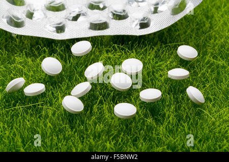 Weiße Antibiotika Pillen und leere Blisterpackung verstreut auf dem grünen Rasen Stockfoto