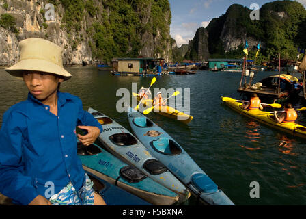 Touristen in mehrere Kajaks aus einem Ausflugsboot in Vietnam Halong-Bucht. Rennfahrer paddeln Seekajaks in der Halong Bay während eines Abenteuers Stockfoto