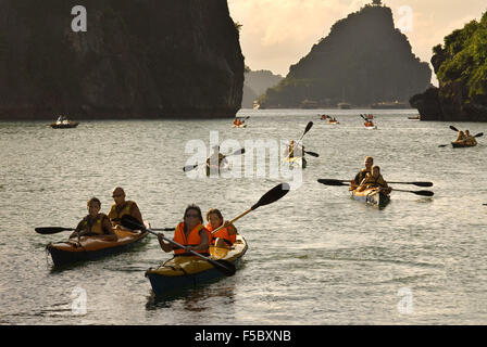 Touristen in mehrere Kajaks aus einem Ausflugsboot in Vietnam Halong-Bucht. Rennfahrer paddeln Seekajaks in der Halong Bay während eines Abenteuers Stockfoto