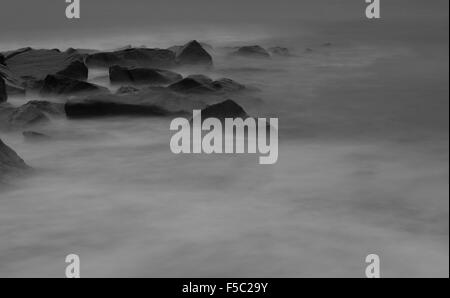 unheimliche nebligen Vordergrund Wellen rund um große Felsen im Meer Stockfoto