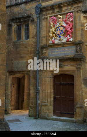 Einen kleinen abgeschiedenen Innenhof in Sherborne School. Über eine Tür ist das königliche Wappen von König Edward 6. Dorset, England, Vereinigtes Königreich. Stockfoto