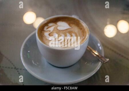 Cappuccino Kaffee mit aufgeschäumter Milch, Kaffee-Kunst, in einer Schale auf einem hellen Hintergrund mit Licht reflektiert den Zähler. Stockfoto