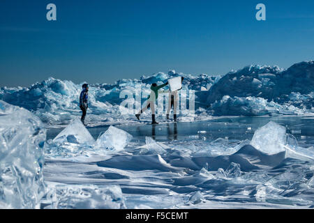 Zwei Erwachsene Männer spielen mit Eisbrocken Teller stapelten sich aus einem Druck-Grat entlang Lake Superior, North Shore im Winter, Stockfoto