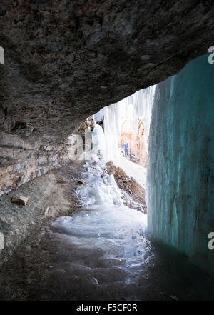 Frau nähert sich den Eintrag auf dem Weg hinter die gefrorenen Minnehaha Fälle im Winter, Minneapolis, MN, USA Stockfoto