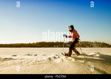 Eine Frau Bündel in ein rosa Fell Schneeschuhen über Schnee auf einem Subzero Wintertag, Ely, MN, USA Stockfoto