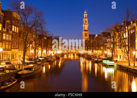 Die Westerkerk (Westkirche) entlang des Kanals der Prinsengracht in Amsterdam bei Nacht. Stockfoto