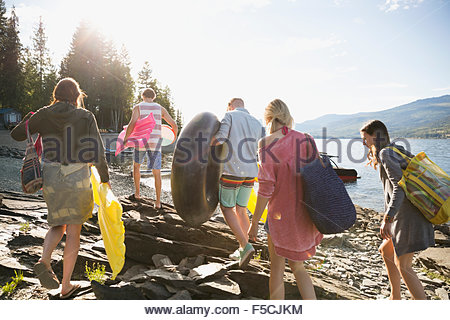 Junge Freunde tragen Pool Flöße am sonnigen Seeufer