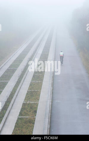 Cambridgeshire, Großbritannien. 2. November 2015. Ein einsamer Radfahrer Köpfe in Richtung Cambridge unterwegs im dichten Nebel im Laufe des Vormittags geführte Bus pendeln. Die milden Anfang bis November dürfte weiterhin mit mehr Herbst Nebel am Morgen Morgen. Bildnachweis: Julian Eales/Alamy Live-Nachrichten Stockfoto