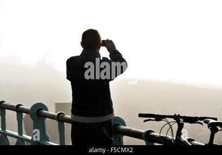 Brighton Sussex UK Montag, 2. November 2015 - ein Mann nimmt ein Foto des Nebels mit einem Smartphone auf Brighton Seafront am frühen Morgen Nebel schwere Reise Störungen in ganz Großbritannien heute Morgen vor allem an den großen Flughäfen verursacht und auf den wichtigsten Straßen Credit: Simon Dack/Alamy Live News Stockfoto