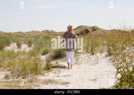 Ein Senior Spaziergänge in den Dünen am Strand und genießen Sie die Ruhe Stockfoto