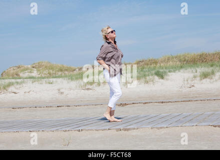 Ein Senior Spaziergänge in den Dünen am Strand und genießen Sie die Ruhe Stockfoto