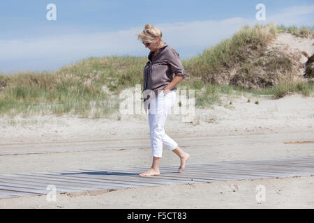 Ein Senior Spaziergänge in den Dünen am Strand und genießen Sie die Ruhe Stockfoto