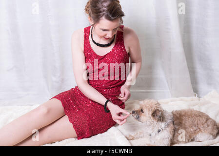 Frau im roten Kleid, die Fütterung des Hundes auf Decke Stockfoto