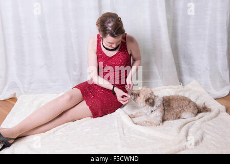 Frau im roten Kleid, die Fütterung des Hundes auf Decke Stockfoto