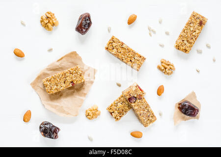 Müsliriegel oder Energieriegel mit Hafer, Datteln und Nüssen auf weißem Holz Hintergrund, Ansicht von oben. Snack für Yoga, Fitness oder Sport Stockfoto