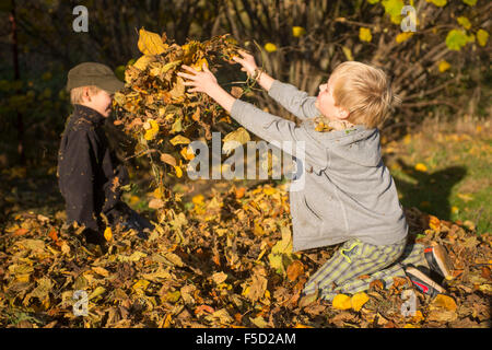 Zwei Kinder Jungs spielen, werfen Herbst fährt vom Stapel in den Garten, herbstliche Spaß, glücklich Stockfoto