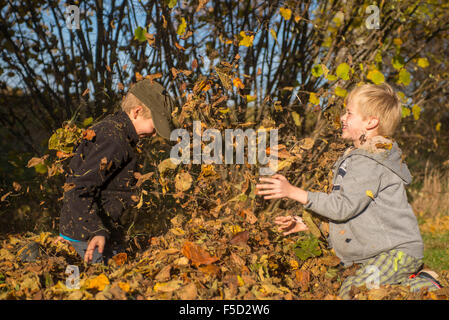 Zwei Kinder Jungs spielen, werfen Herbst fährt vom Stapel in den Garten, herbstliche Spaß, glücklich Stockfoto