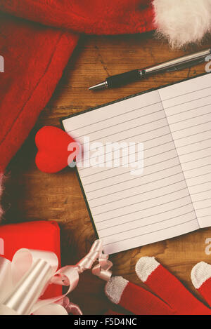 Santa Claus Schreibtisch, leeren Notizbuch als Kopie Raum für gute Kinder-Wunschliste, Mütze und Handschuhe mit Weihnachtsgeschenken und präsentieren Stockfoto