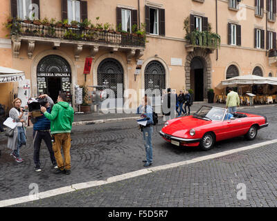 Filmteam und männliche Models in einer klassischen Alfa Romeo Sportwagen auf der Piazza Navona in Rom, Italien Stockfoto