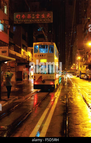 Nacht Straßenbahn im Regen auf eine gelbe Straße in Hongkong. Stockfoto