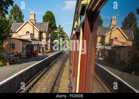 Das Bahnhofsgebäude in Hampton Loade reflektiert in den Fenstern der Wagen von einem Zug in der Plattform Stockfoto