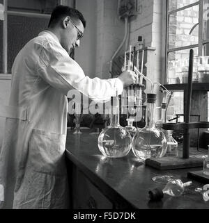 1950, historische, männliche Wissenschaftler im weißen Mantel an der Arbeit in einem chemischen Labor, England, UK, Mischen von verschiedenen Flüssigkeiten. Stockfoto