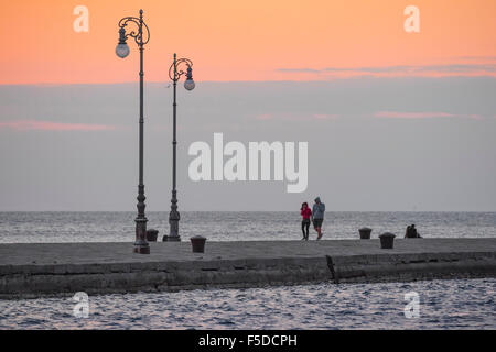 Paare, die Dämmerung, Dämmerung ein junges Paar machen Sie einen Spaziergang entlang der Molo Audace in Triest, Italien. Stockfoto