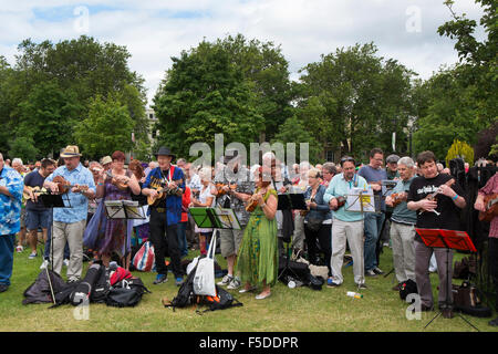 Menschen spielen Ukulelen an den grossen Busk, Teil der Ukulele Festival von Großbritannien in Cheltenham, Gloucestershire, Vereinigtes Königreich Stockfoto