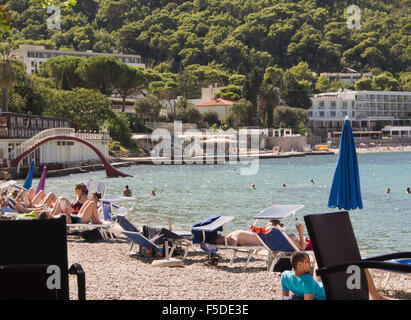 Kiesstrand mit Sonnenanbetern Azure Blau des Meeres und der charakteristischen Beton Folie auf Lapad Strand, Dubrovnik Kroatien Stockfoto