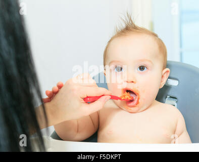 Mutter, die hungrigen sechs Monate altes Baby feste Nahrung Stockfoto