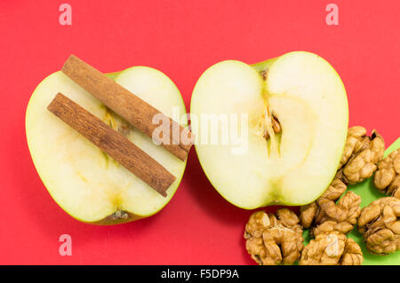 Frische Walnüsse, Zimt und Äpfeln auf rotem Grund. Gesundes dessert Stockfoto