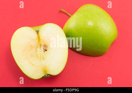 Zwei Hälften eines Apfels auf rotem Grund. Gesunde Ernährung abstrakt Stockfoto