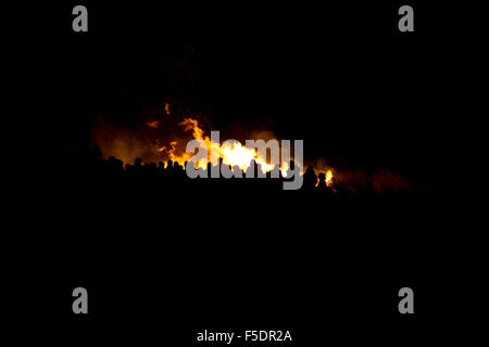 Personen in einer Menschenmenge feiern Lagerfeuer Nacht Guy Fawkes, Stand in einer Menschenmenge als Silhouette vor einem Lagerfeuer mit hohen Flammen. Stockfoto